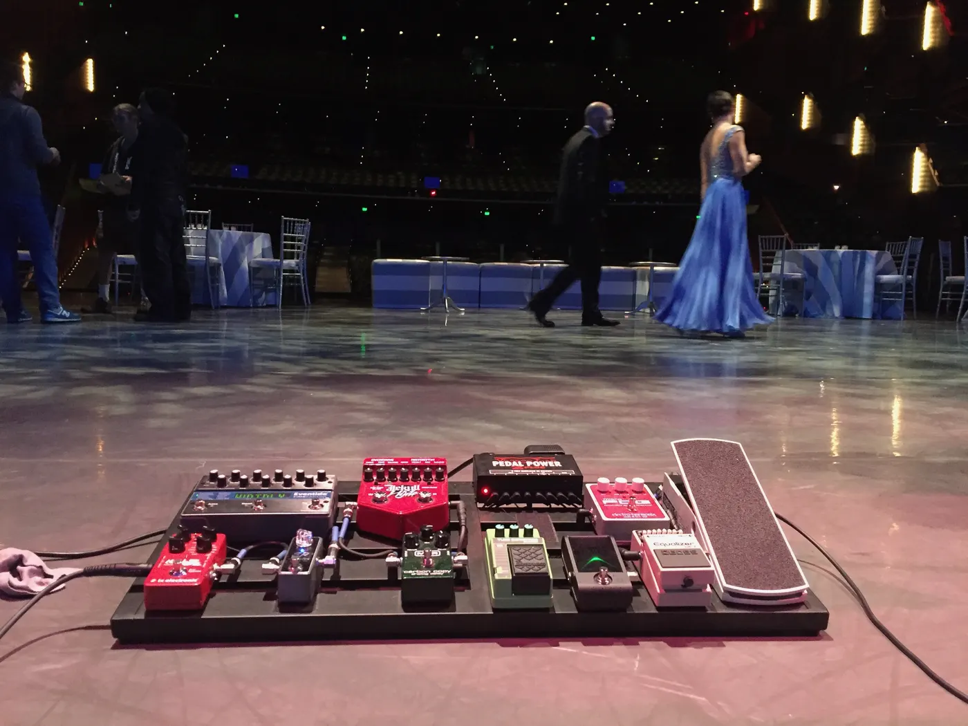 A guitar pedalboard on a ballroom floor during an evening event