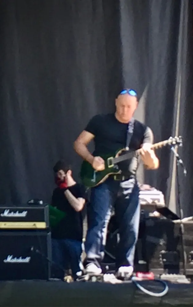 Playing a green electric guitar on stage in front of Marshall amplifiers